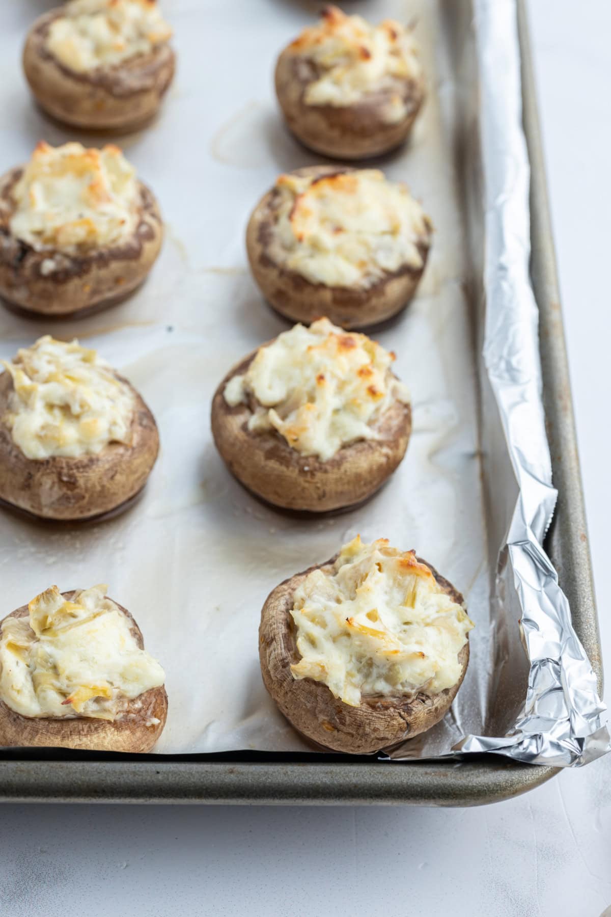 Artichoke Stuffed Mushrooms recipe from RecipeGirl.com artichoke stuffed mushrooms on baking sheet