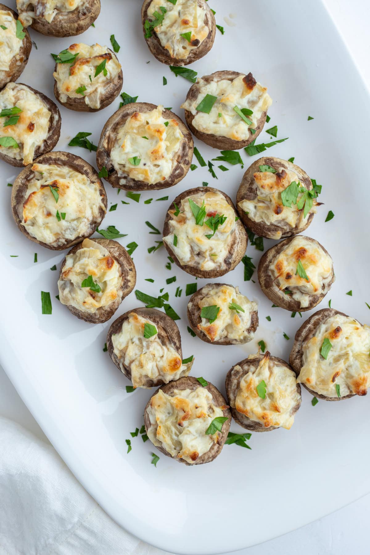 Artichoke Stuffed Mushrooms recipe from RecipeGirl.com overhead shot of artichoke stuffed mushrooms on white platter