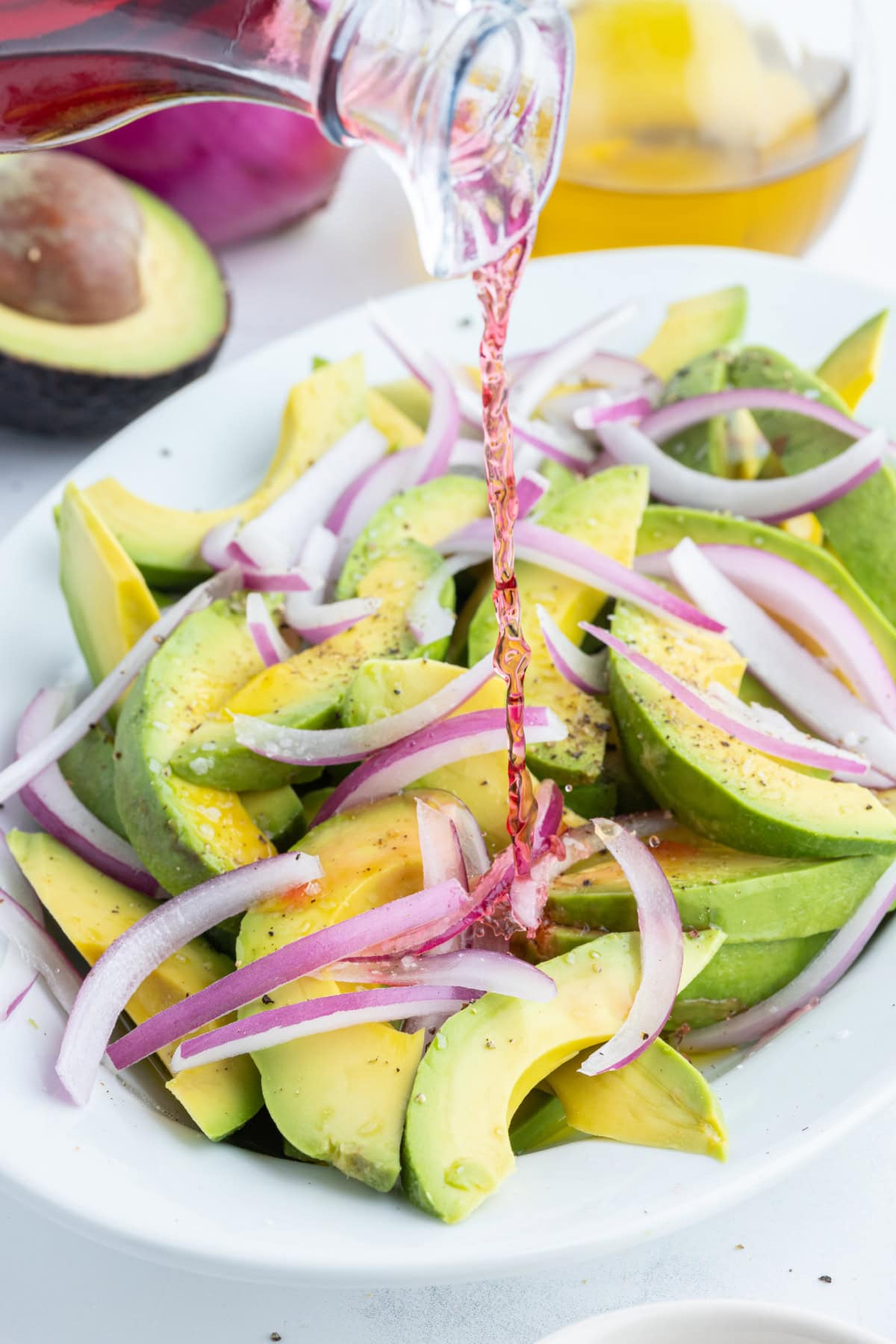 Avocado and Onion Salad recipe from RecipeGirl.com pouring dressing onto avocado and onion salad