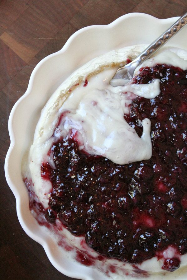 Baked Brie with Blueberry Sauce recipe from RecipeGirl.com #brie #blueberry #summer #appetizer #recipe #RecipeGirl overhead shot of baked brie with blueberry sauce in a scalloped white pie dish