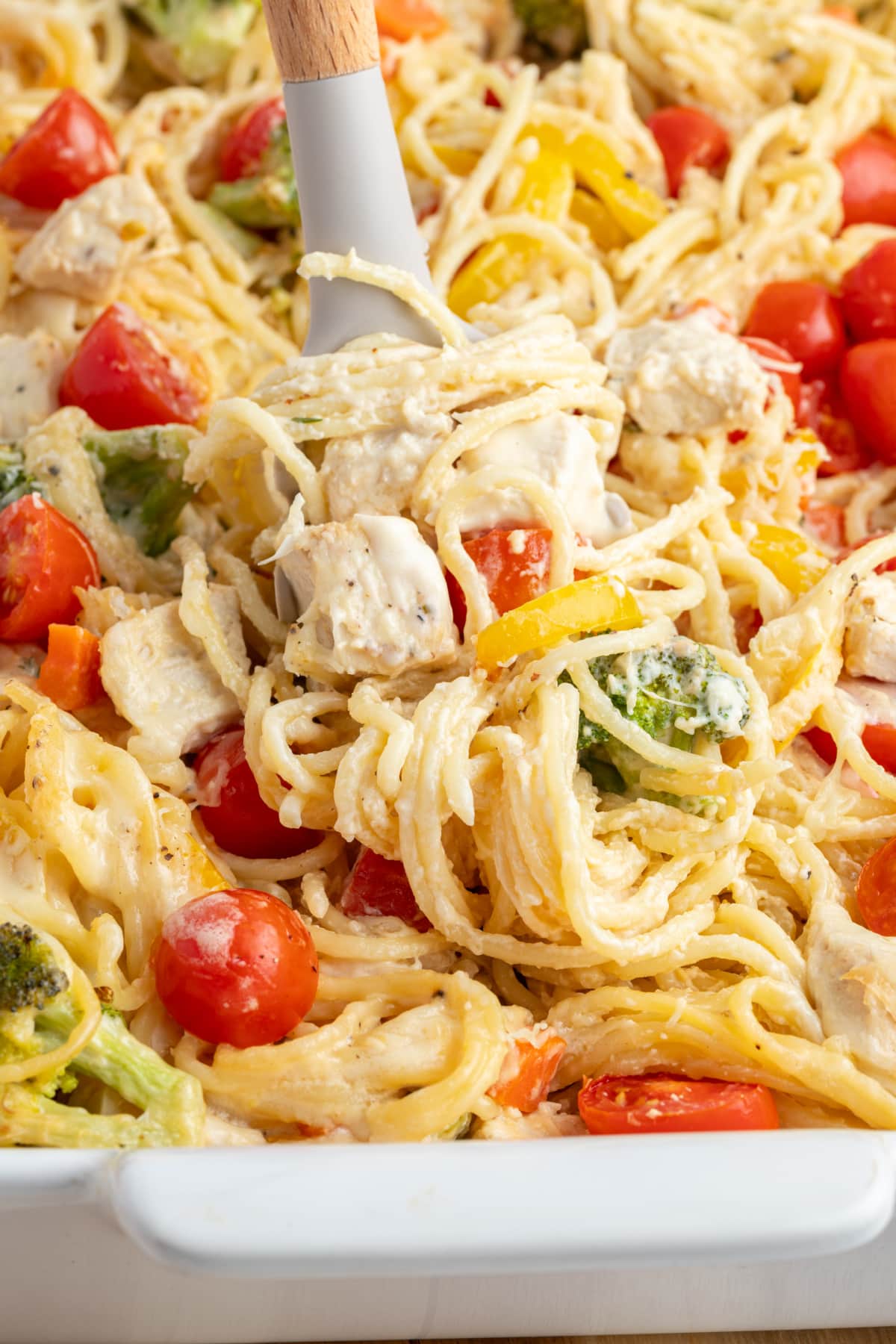 Baked Lemon Chicken Spaghetti Primavera recipe from RecipeGirl.com baked lemon chicken spaghetti primavera in baking dish with serving spoon