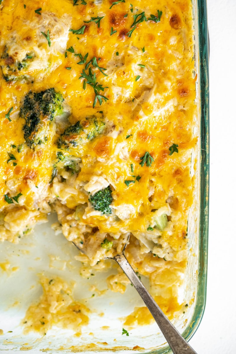 Cheesy Chicken and Broccoli Rice Casserole recipe from RecipeGirl.com #cheesy #chicken #broccoli #rice #casserole #recipe #RecipeGirl chicken broccoli and rice cheesy casserole in a casserole dish with serving taken out
