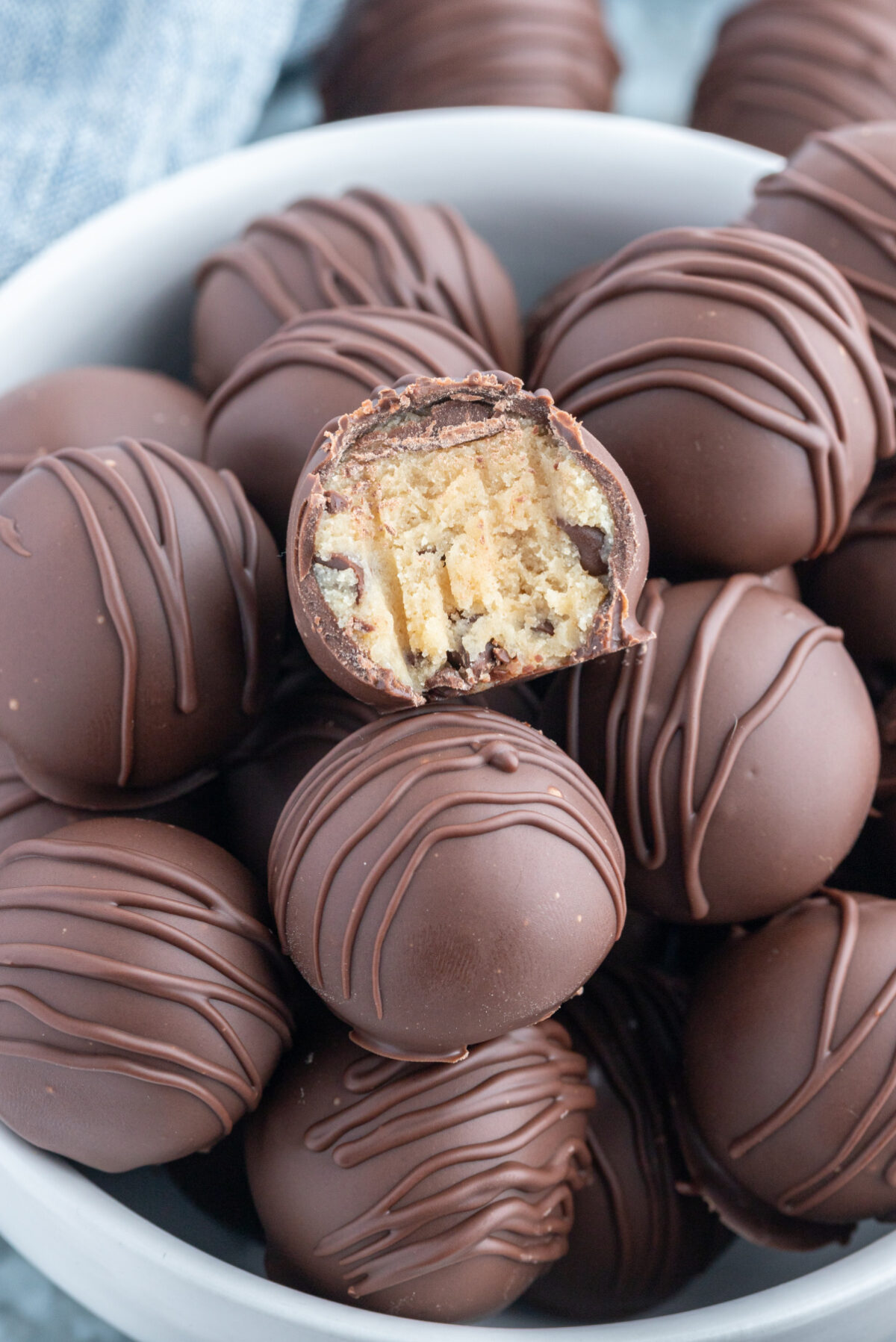 Chocolate Chip Cookie Dough Truffles recipe from RecipeGirl.com flour safe to eat : chocolate covered chocolate chip cookie dough lovers bowl of chocolate chip cookie dough truffles one with bite taken out of it