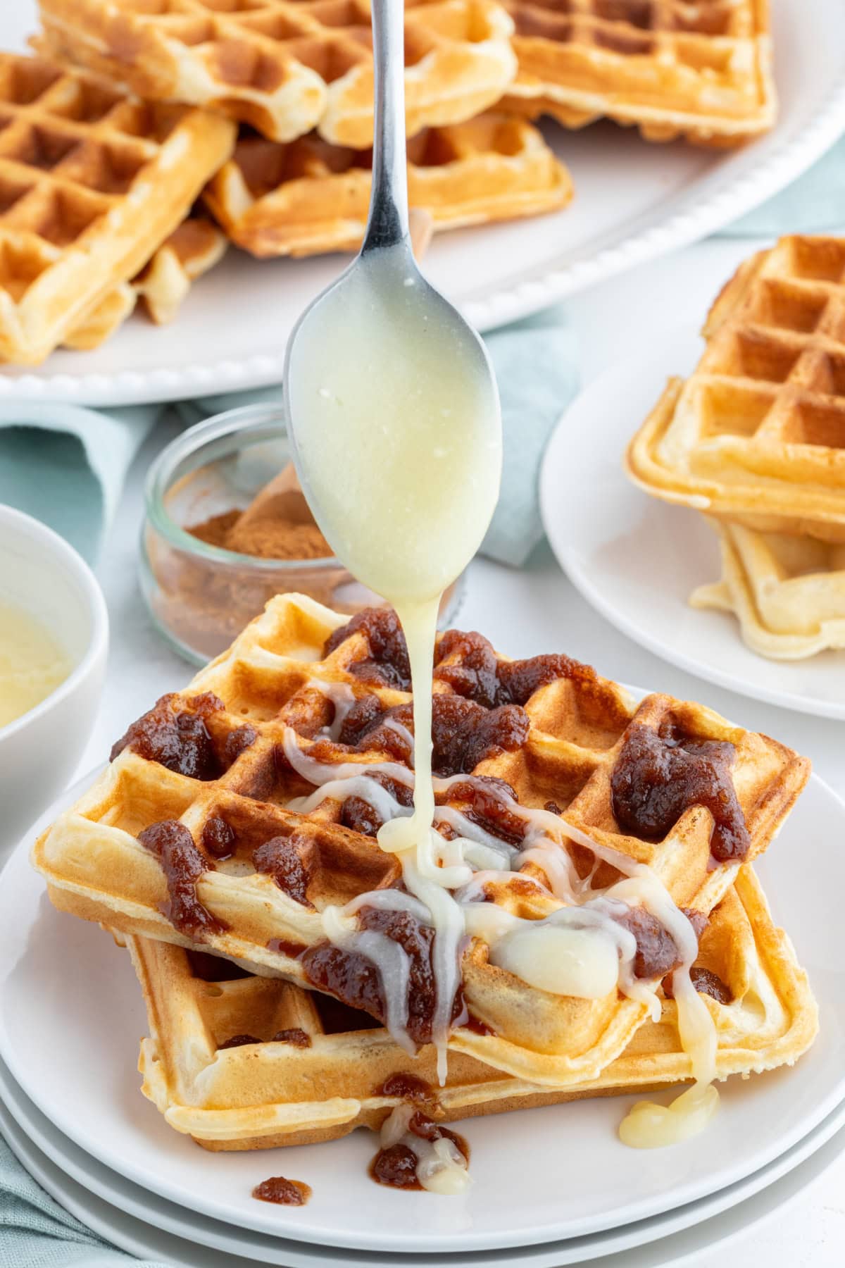 Cinnamon Roll Waffles recipe from RecipeGirl.com drizzling icing onto cinnamon roll waffle