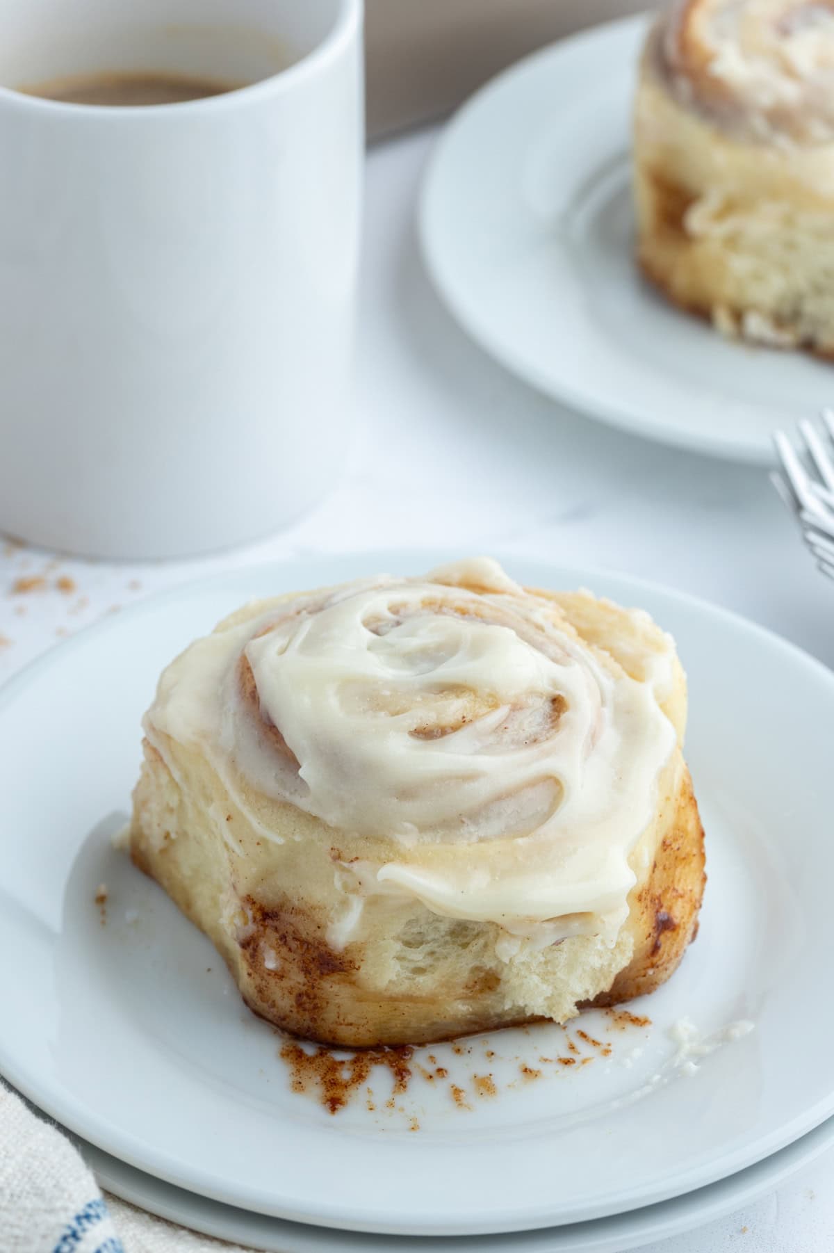 Copycat Cinnabon Cinnamon Rolls recipe from RecipeGirl.com cinnamon roll on plate with icing