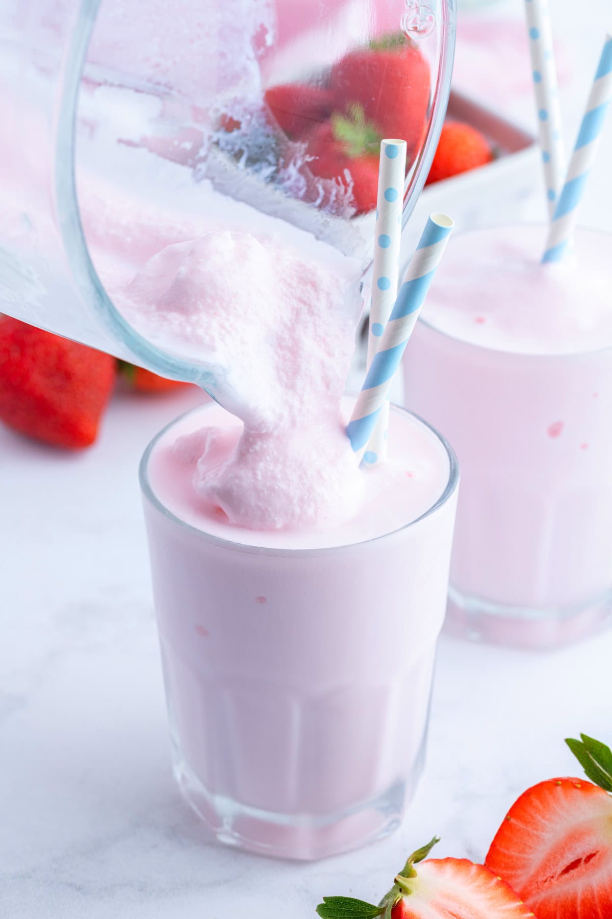 Copycat Wendy's Strawberry Frosty recipe from RecipeGirl.com pouring strawberry frosty into glass with straw