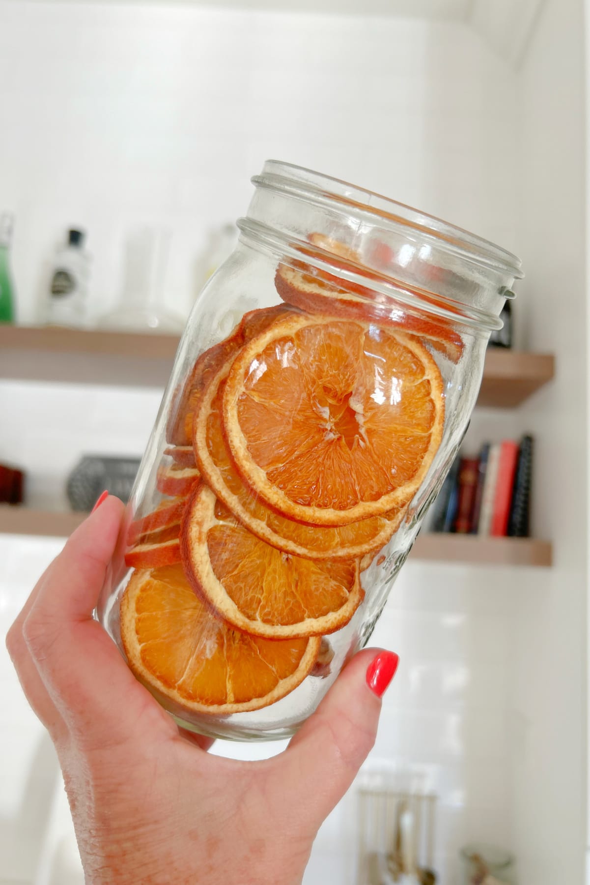 Dehydrated Orange Slices recipe from RecipeGirl.com hand holding jar of dehydrated oranges