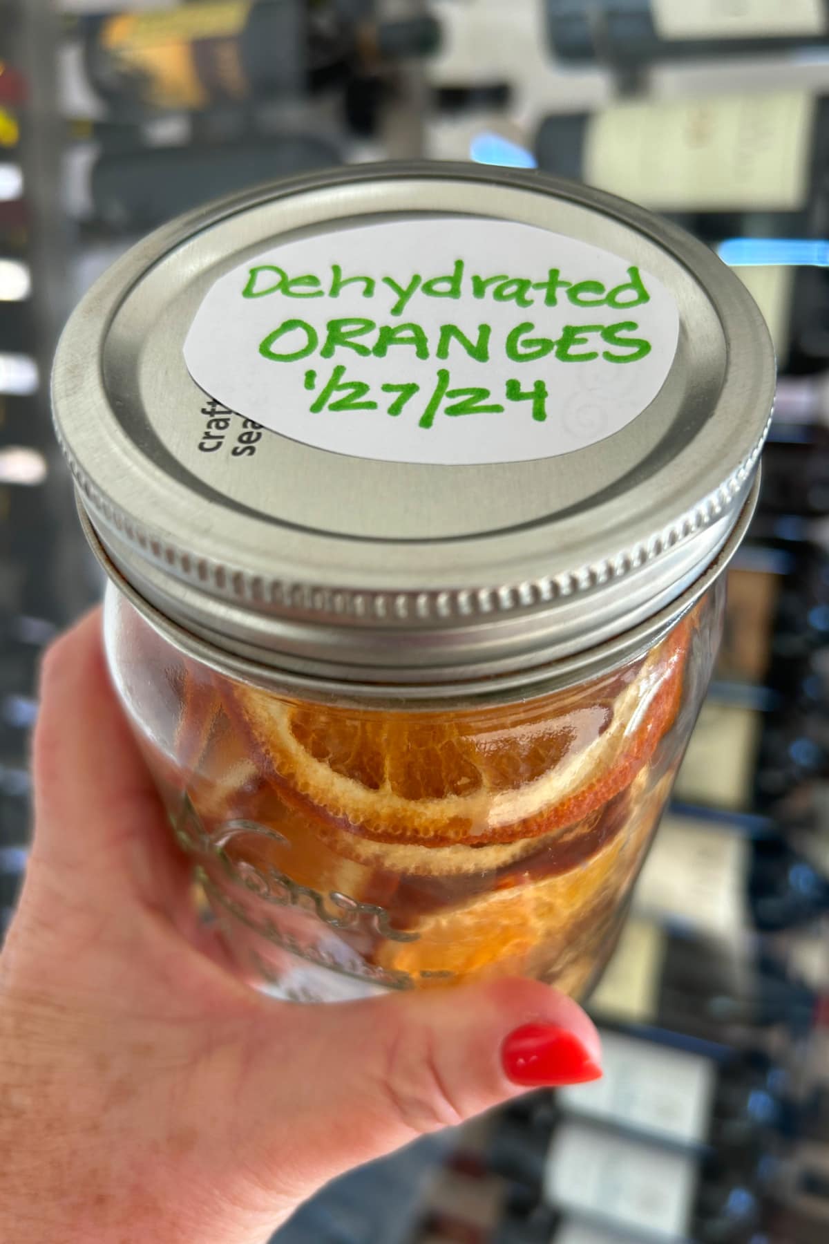 Dehydrated Orange Slices recipe from RecipeGirl.com hand holding jar of dehydrated orange slices