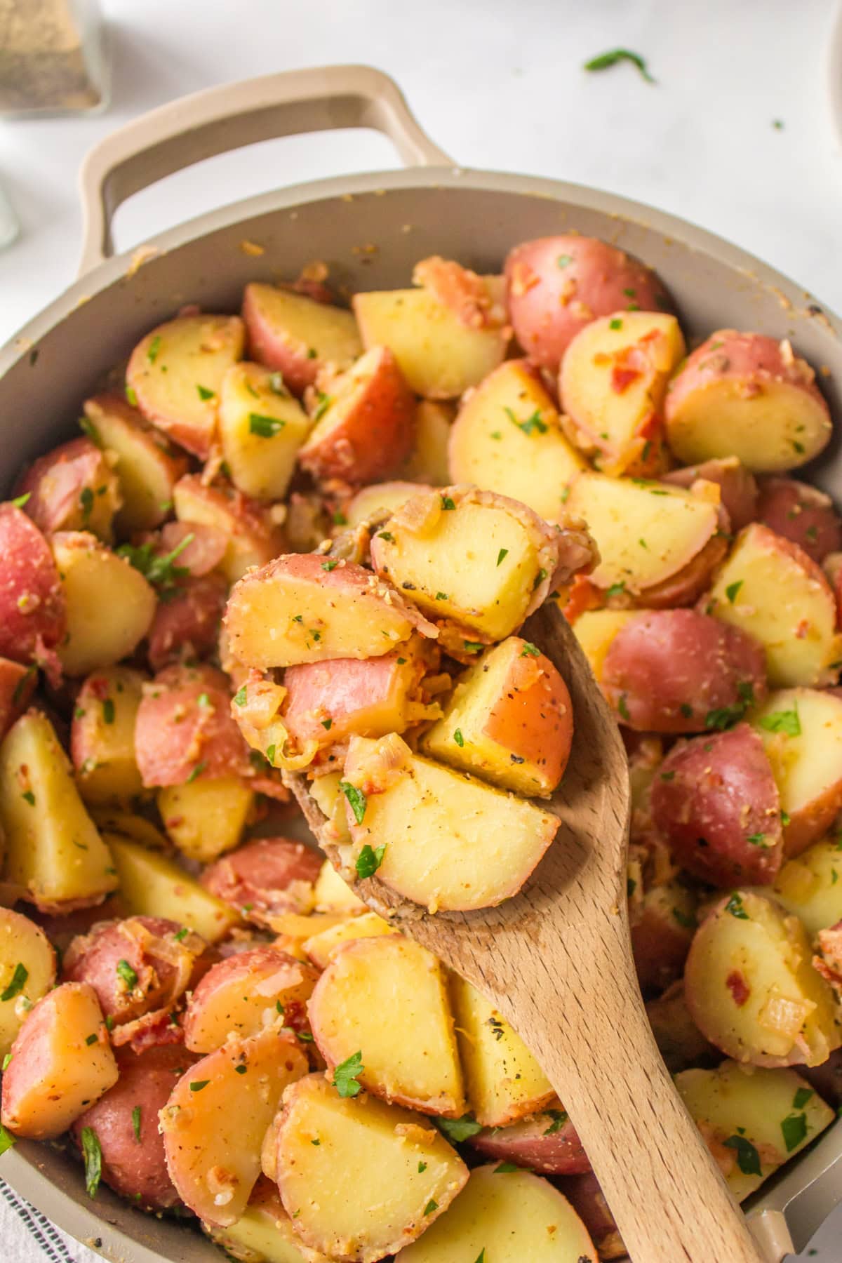 German Potato Salad recipe from RecipeGirl.com wooden spoon in pan of german potato salad