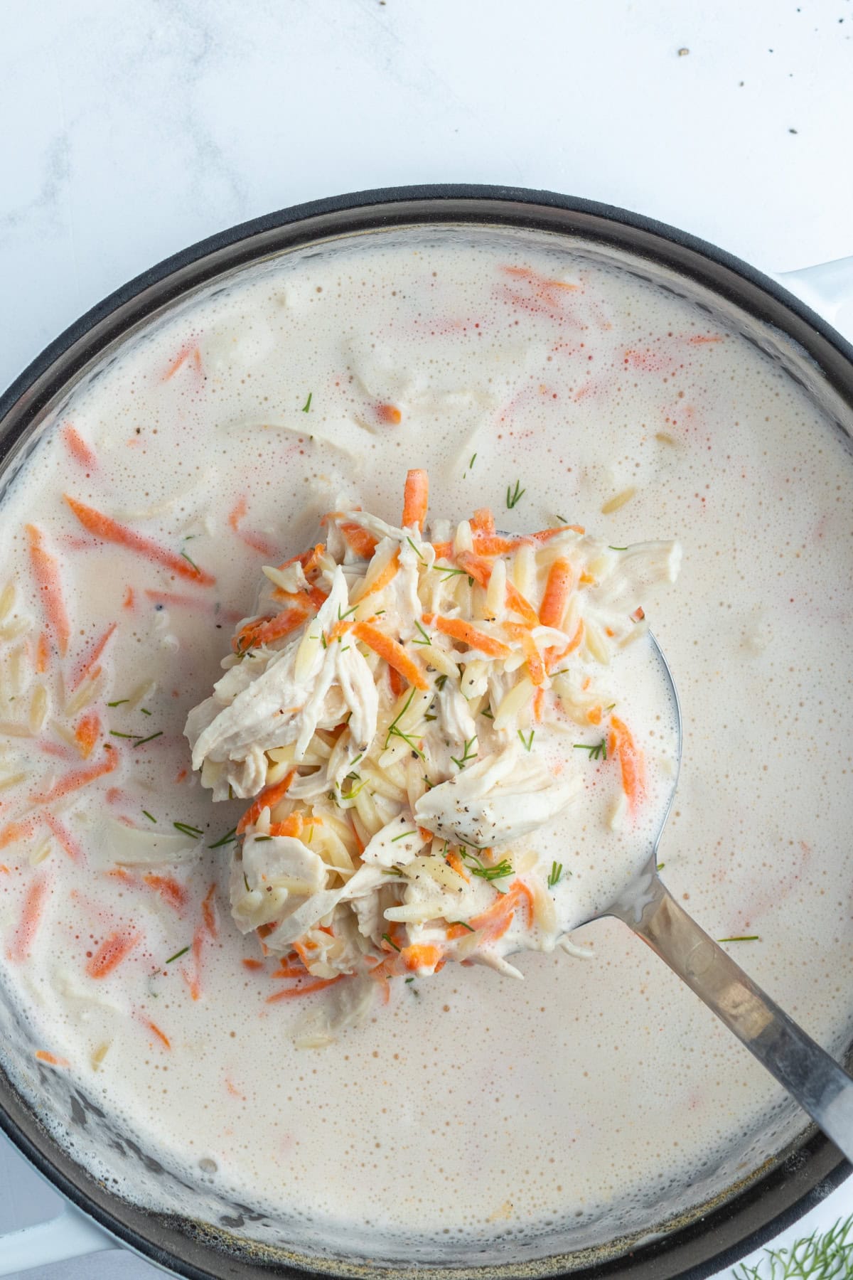 Greek Orzo and Chicken Soup recipe from RecipeGirl.com ladle sitting in pot of greek orzo and chicken soup