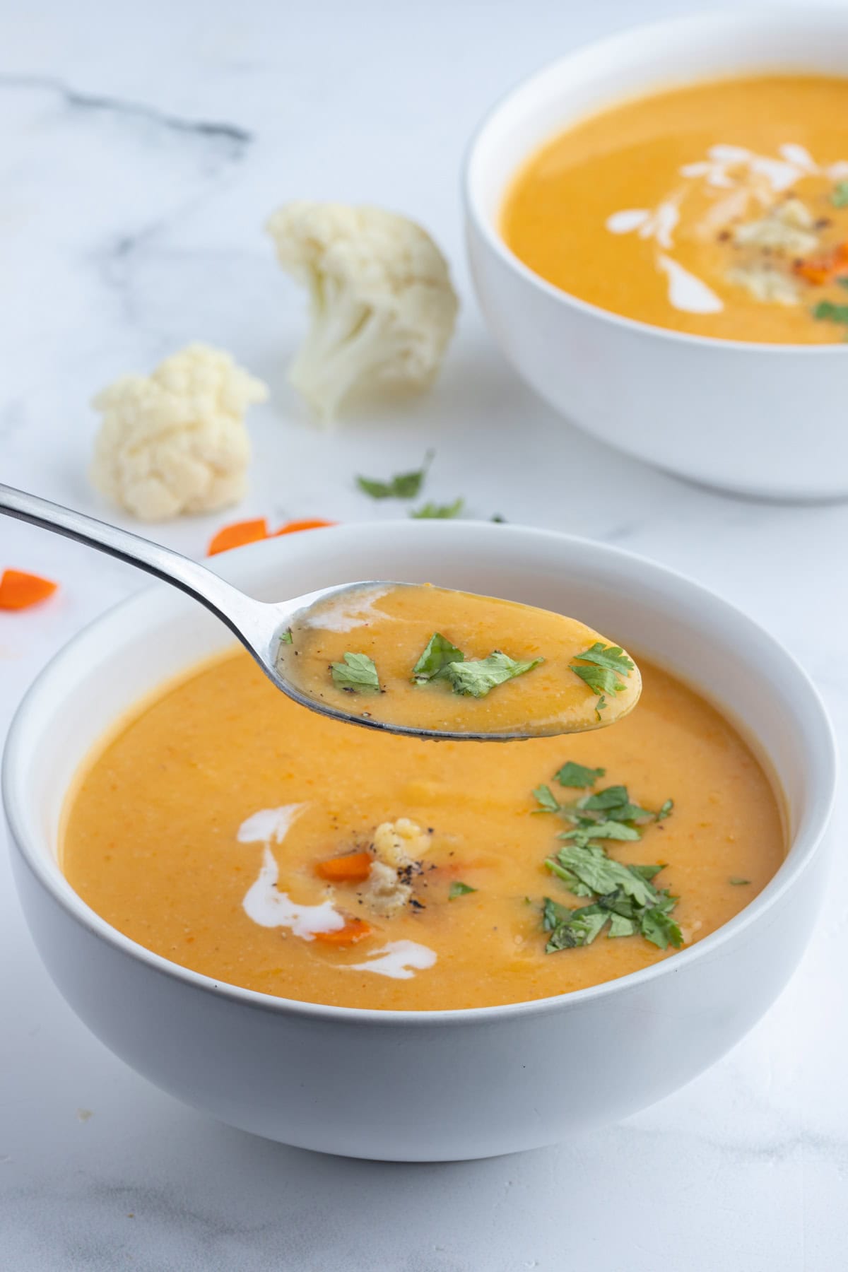Instant Pot Cauliflower and Sweet Potato Soup recipe from RecipeGirl.com spooning out spoonful of cauliflower and sweet potato soup