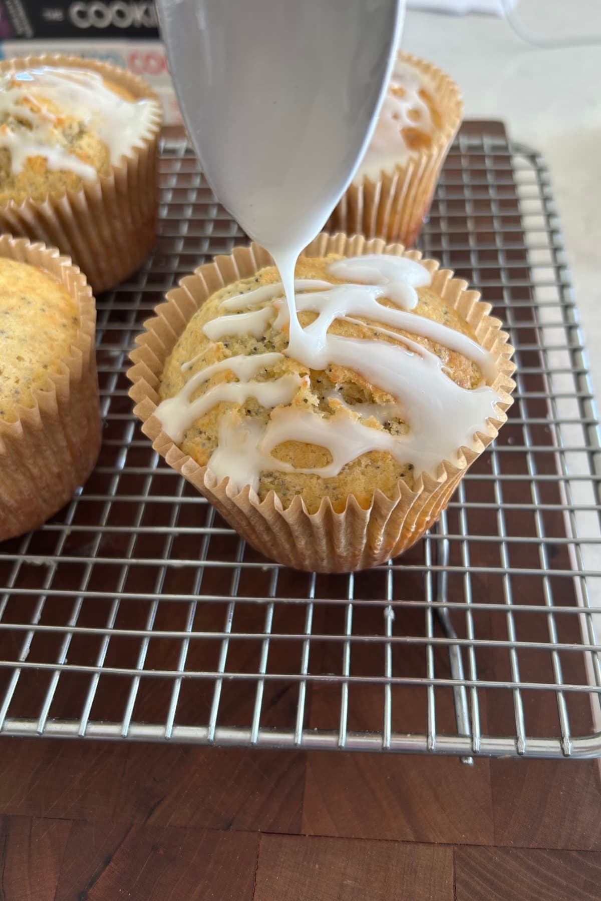 Lemon Poppy Seed Muffins recipe from RecipeGirl.com drizzling glaze onto poppy seed muffins on rack