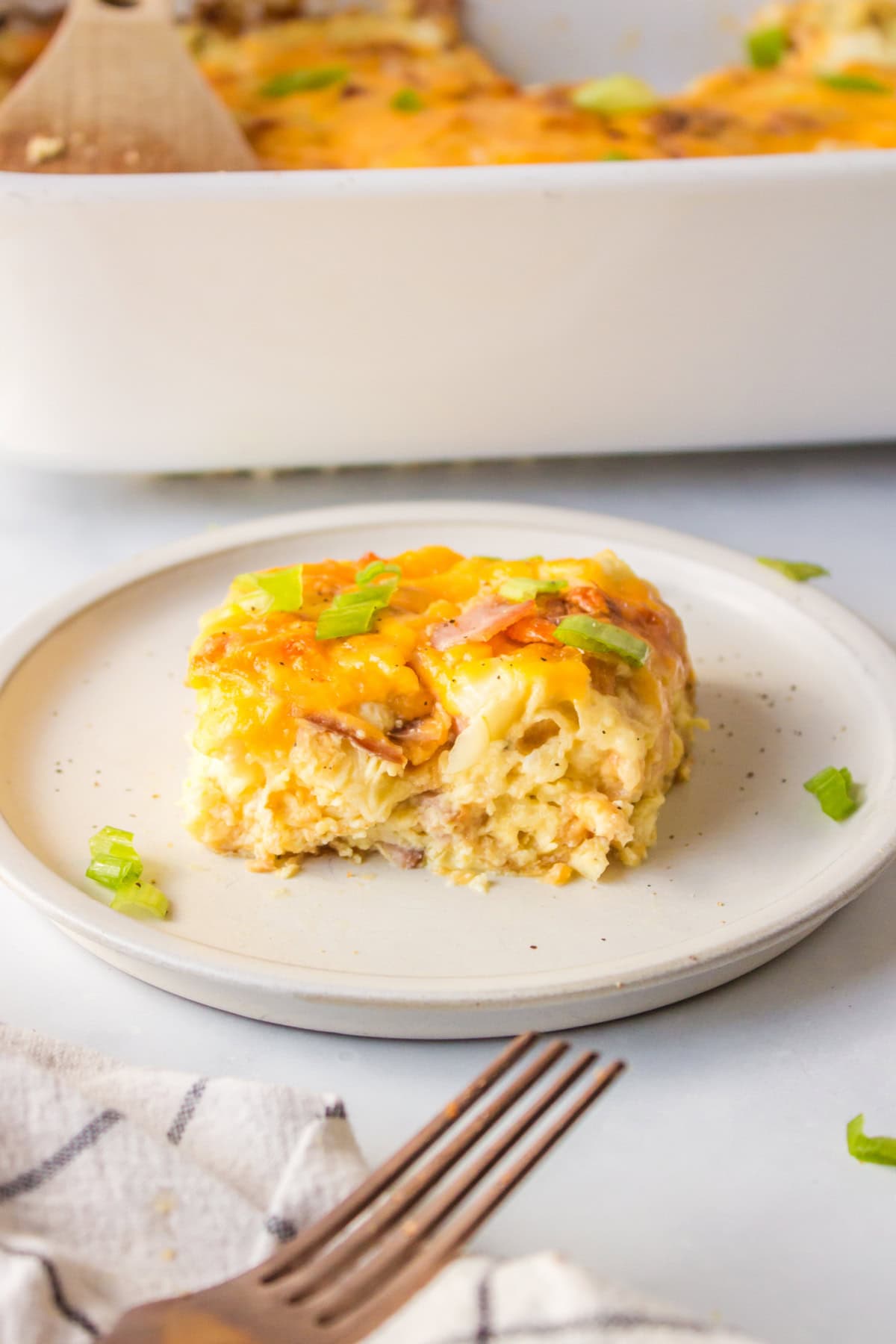 Overnight Croissant Ham and Cheese Breakfast Casserole recipe from RecipeGirl.com slice of overnight croissant ham and cheese breakfast casserole on plate