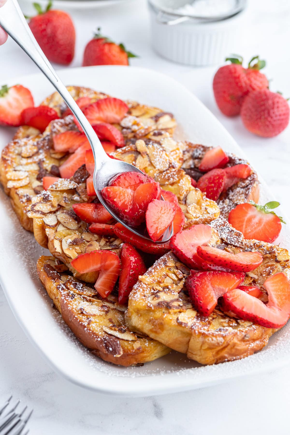 Pain Perdu is a traditional French toast. This is Ina Garten's Barefoot in Paris recipe with strawberries, almonds and Grand Marnier. spooning strawberries onto platter of pain perdu