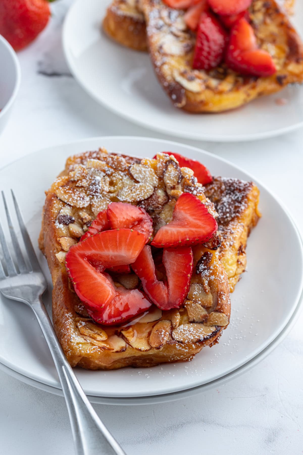 Pain Perdu is a traditional French toast. This is Ina Garten's Barefoot in Paris recipe with strawberries, almonds and Grand Marnier. serving of pain perdu on plate topped with strawberries