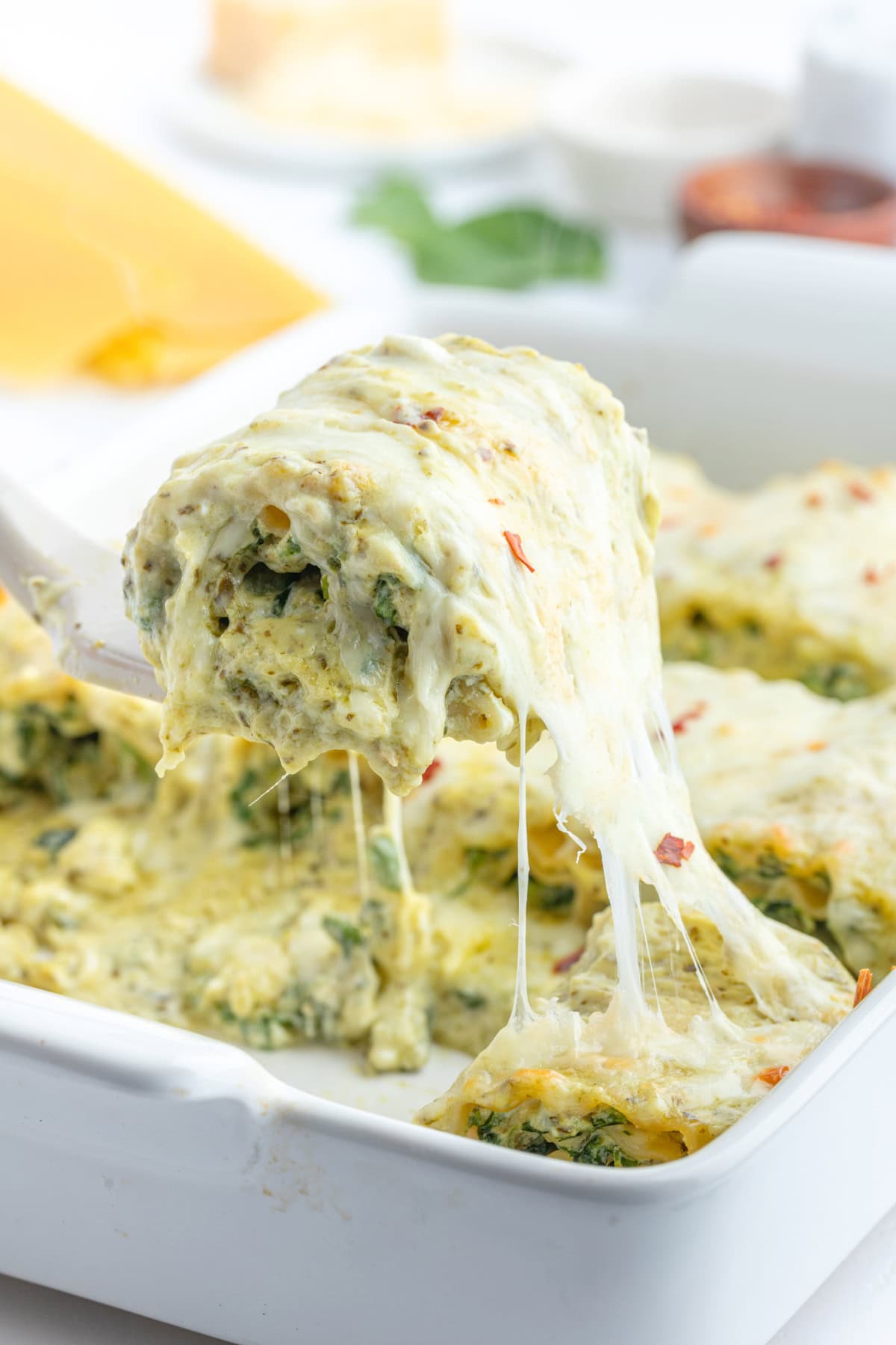 Pesto Lasagna Rolls recipe from RecipeGirl.com spatula pulling pesto lasagna roll from casserole dish