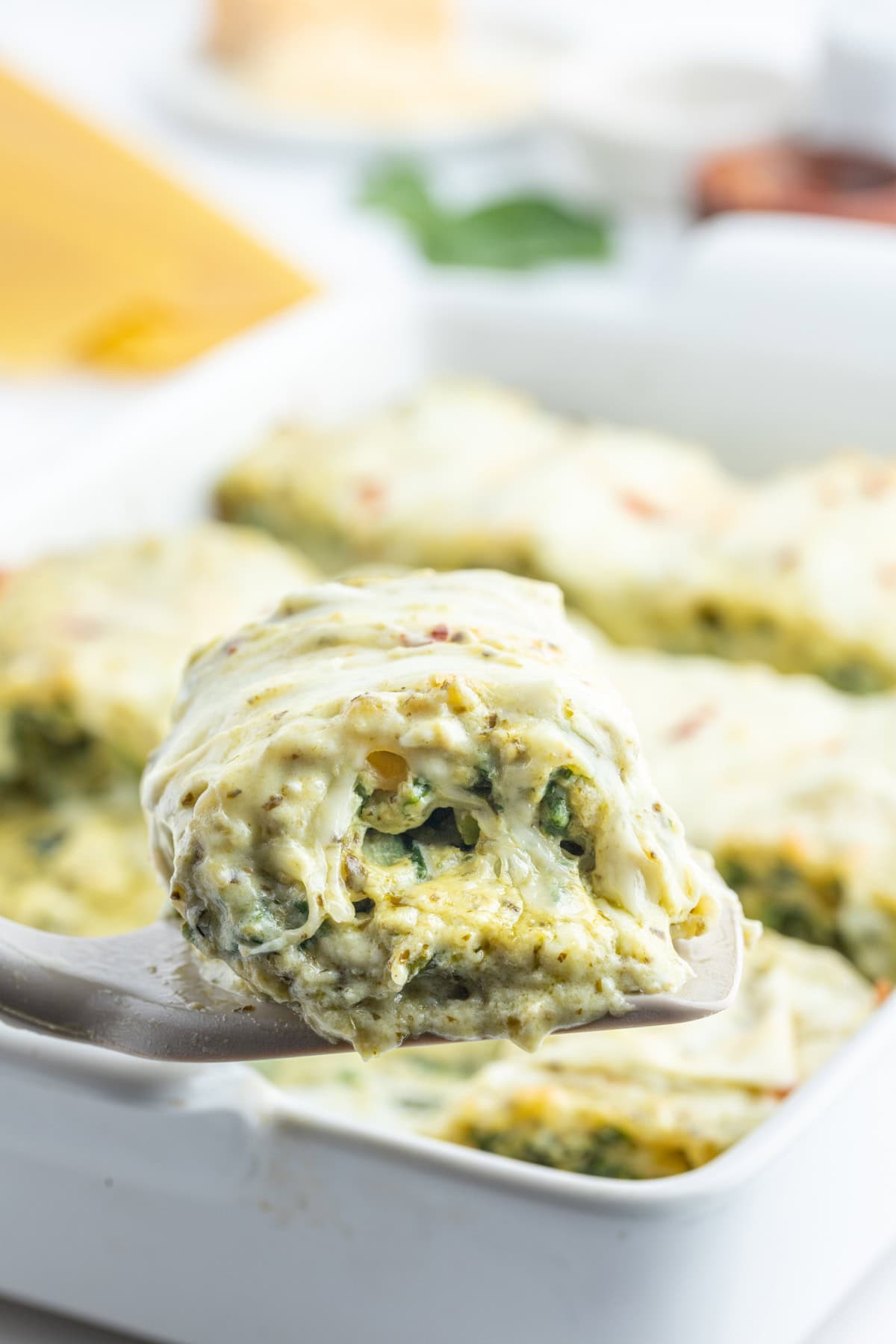 Pesto Lasagna Rolls recipe from RecipeGirl.com spatula taking pesto lasagna roll out of dish