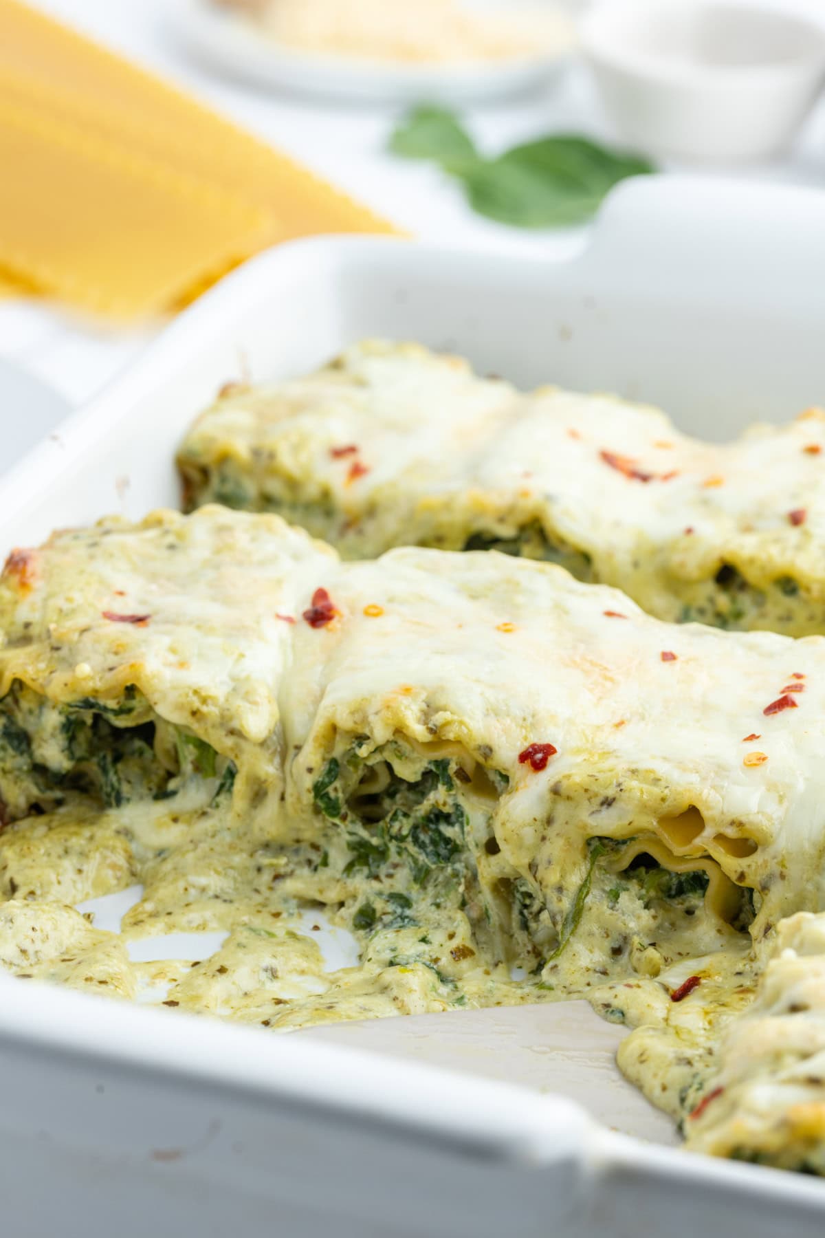 Pesto Lasagna Rolls recipe from RecipeGirl.com casserole dish of pesto lasagna rolls with some taken out