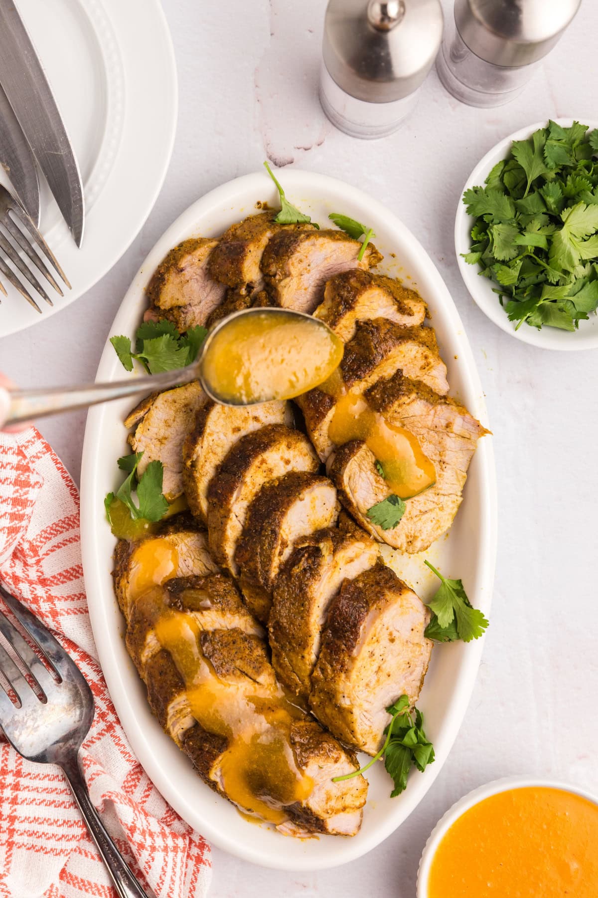Pork Tenderloin with Apricot Ginger Sauce recipe from RecipeGirl.com spooning apricot ginger sauce on top of sliced pork tenderloin on platter