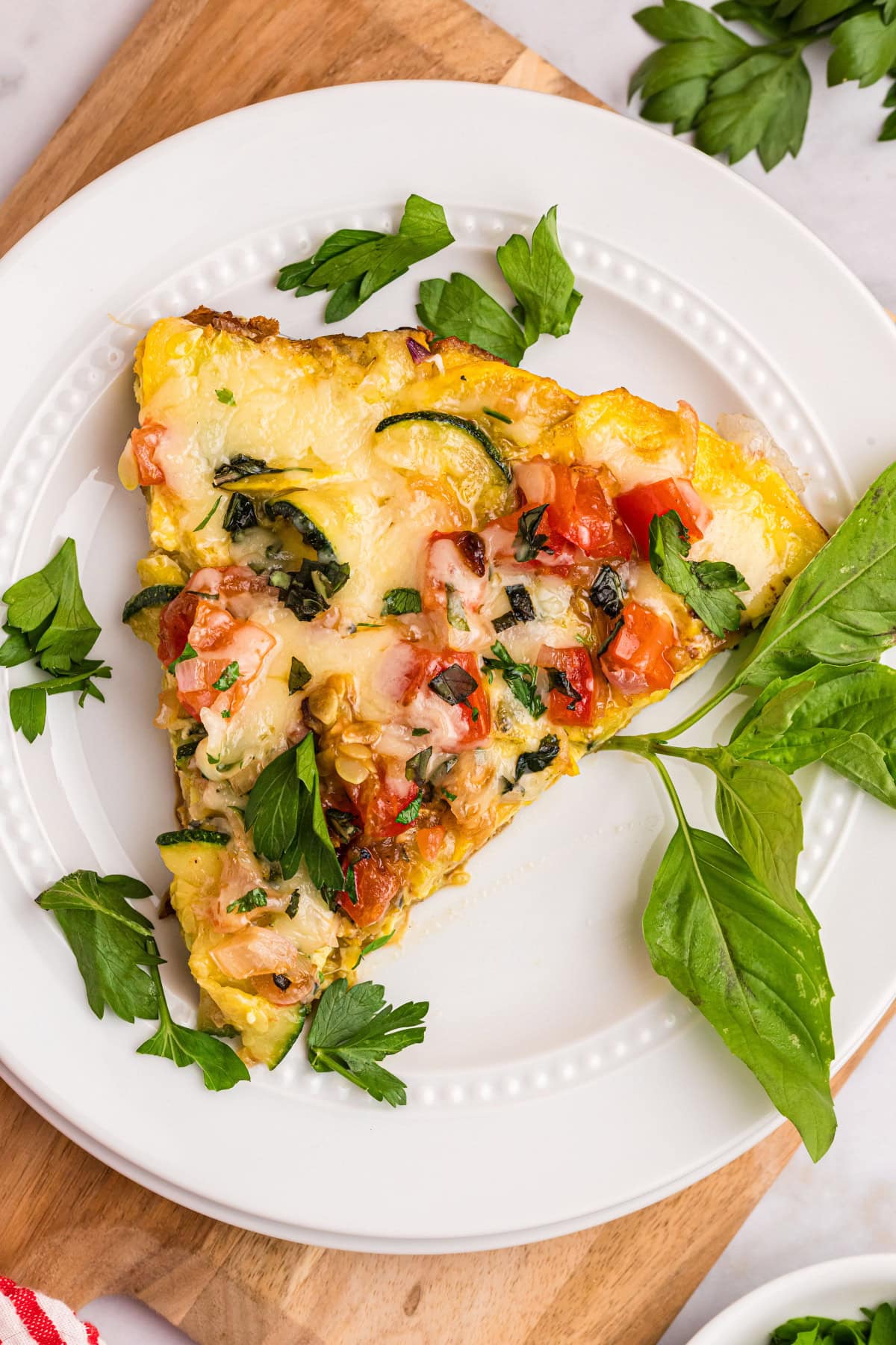 Squash and Tomato Oven Frittata recipe from RecipeGirl.com squash and tomato oven frittata slice on plate with basil leaves