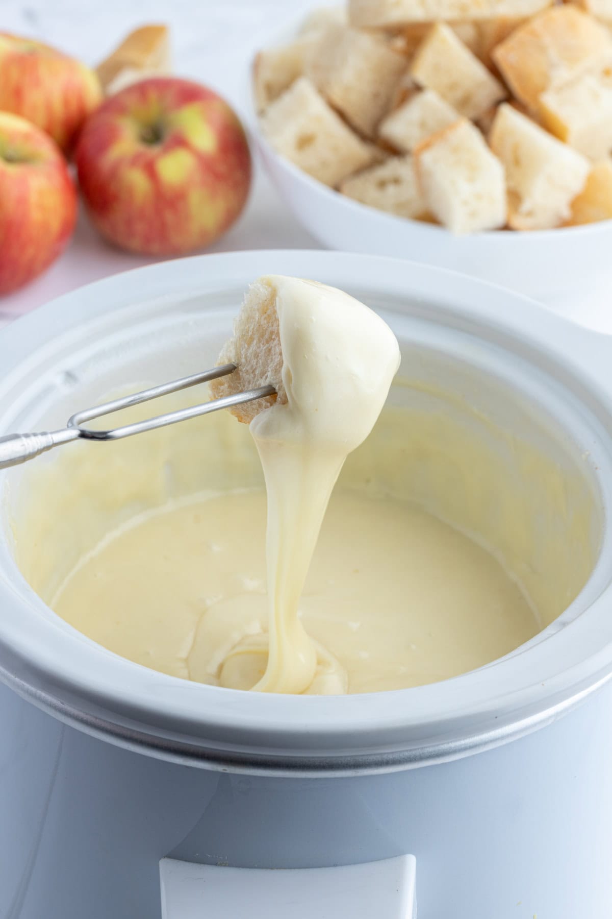 Classic Swiss Fondue recipe from RecipeGirl.com dunking bread into swiss cheese fondue