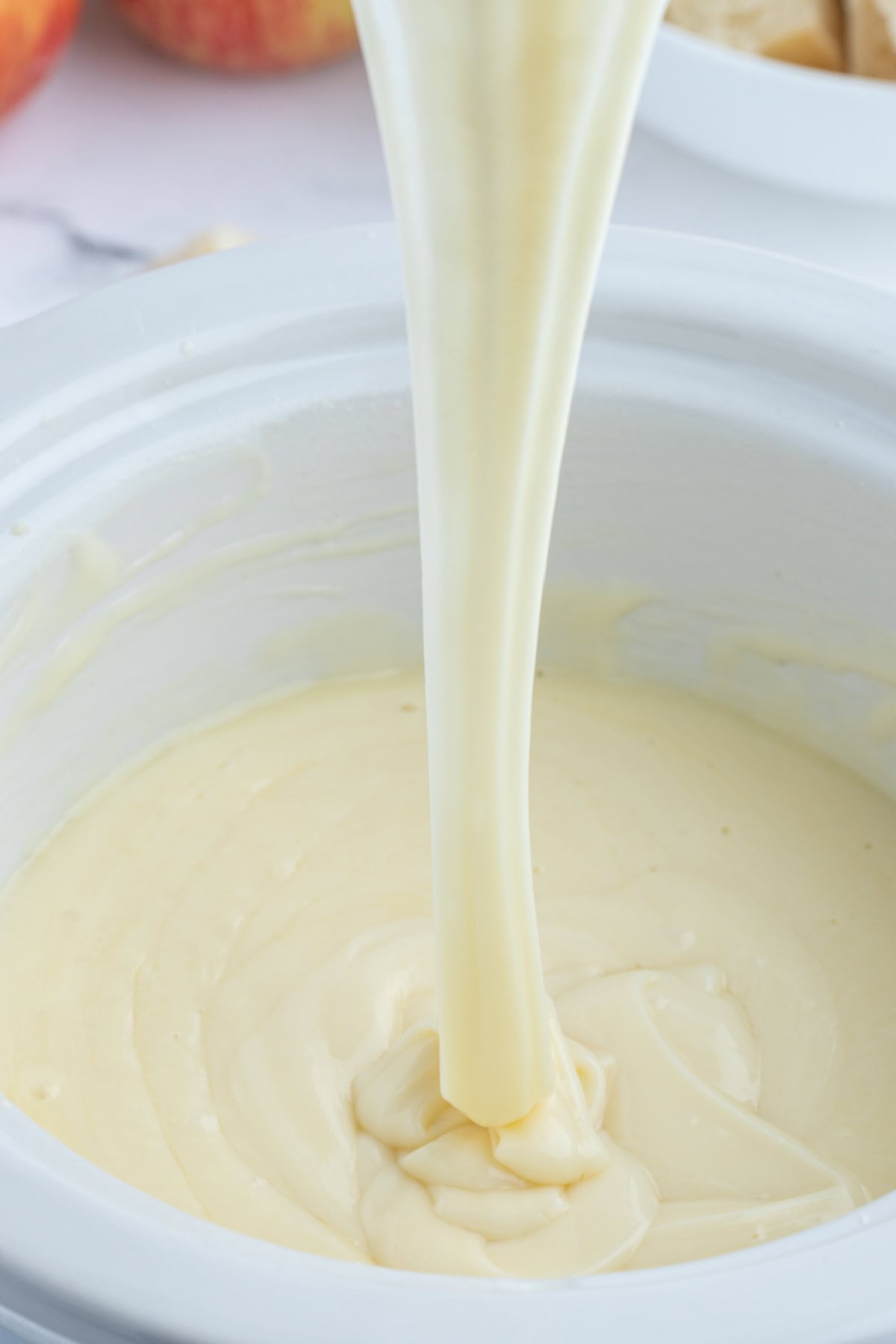 Classic Swiss Fondue recipe from RecipeGirl.com big cheese pull coming out of pot of swiss cheese fondue