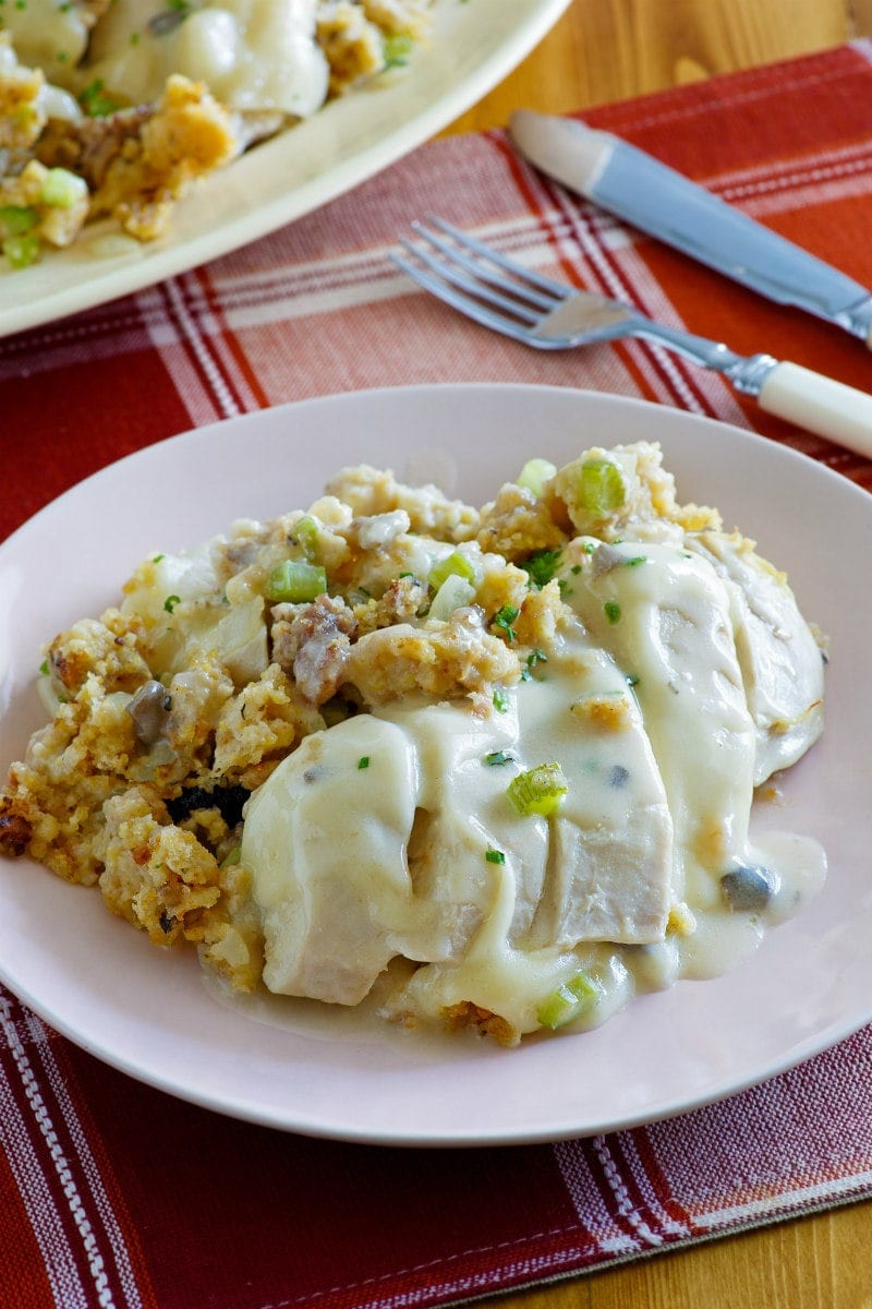 Swiss Chicken Casserole recipe from RecipeGirl.com #swiss #chicken #casserole #recipe #RecipeGirl Serving of Swiss Chicken Casserole on a white plate set on a red and white plaid placemat with a fork and knife