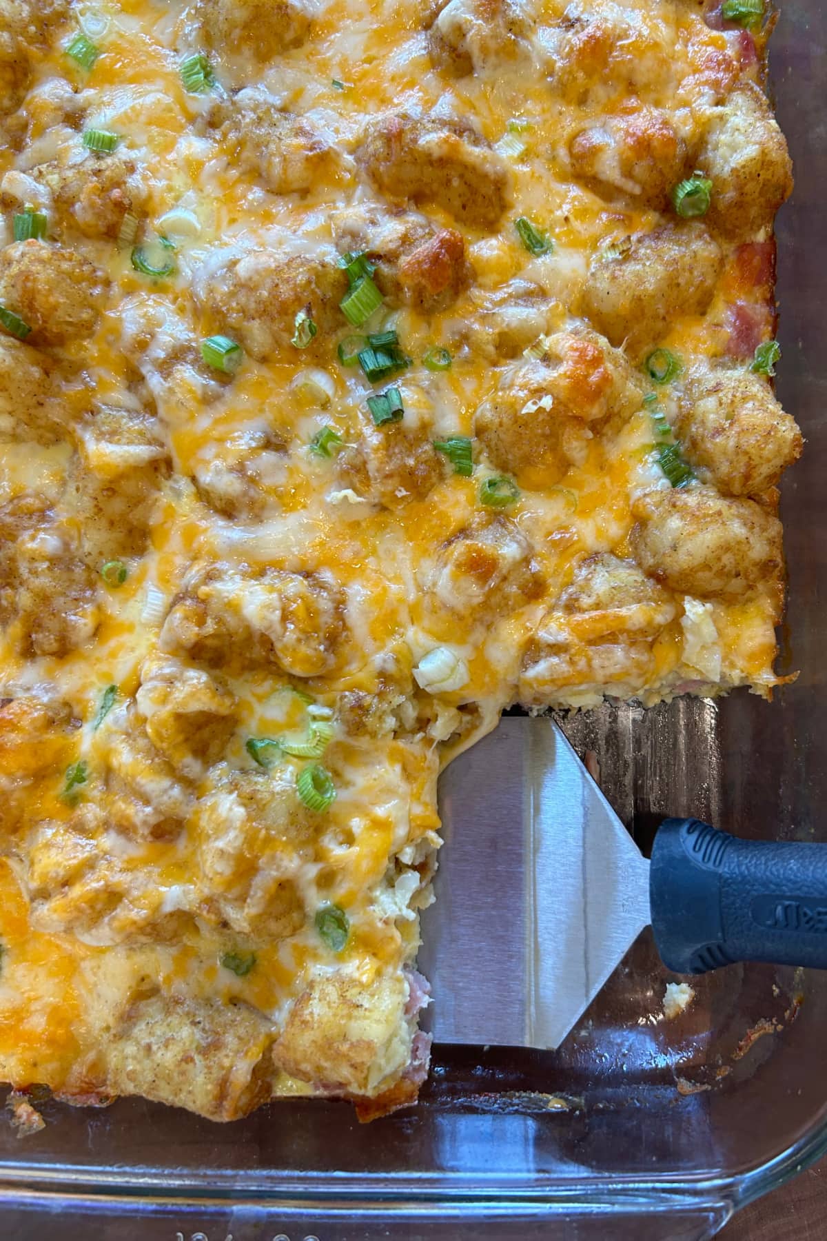 Tater Tot Breakfast Casserole recipe from RecipeGirl.com tater tot breakfast casserole in dish with spatula taking out serving