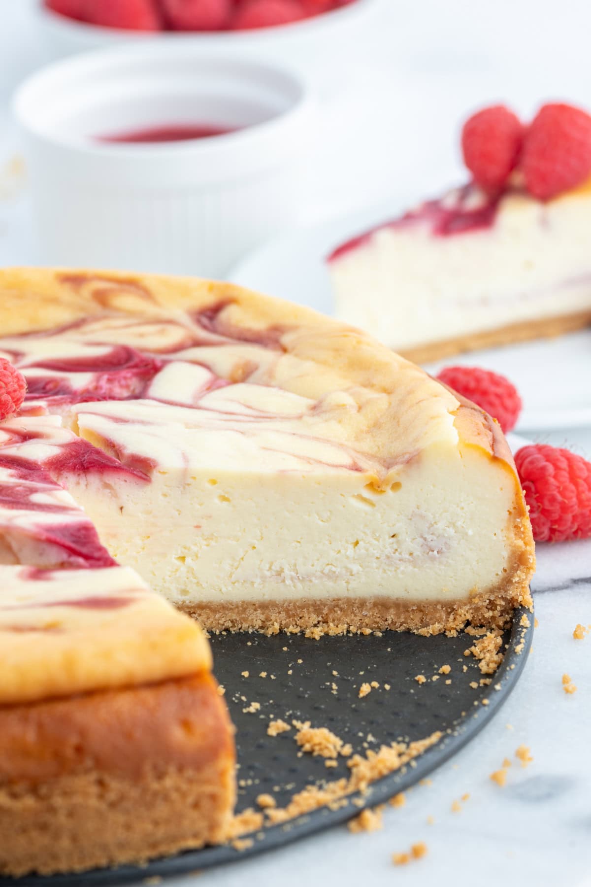 White Chocolate Raspberry Cheesecake recipe from RecipeGirl.com white chocolate raspberry cheescake with large slice taken out